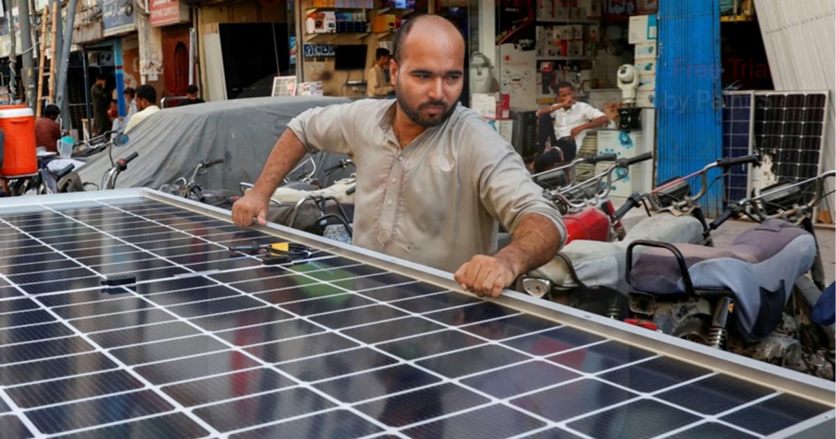 Một công nhân đang lắp tấm pin mặt trời vào xe ở Karachi, Pakistan. Ảnh: Reuters