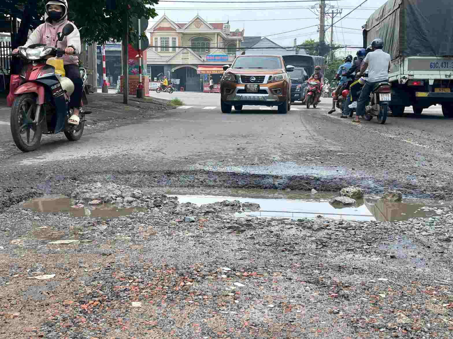 Xe máy phải nép sát vào lề né các hố sâu. Ảnh: Đình Trọng