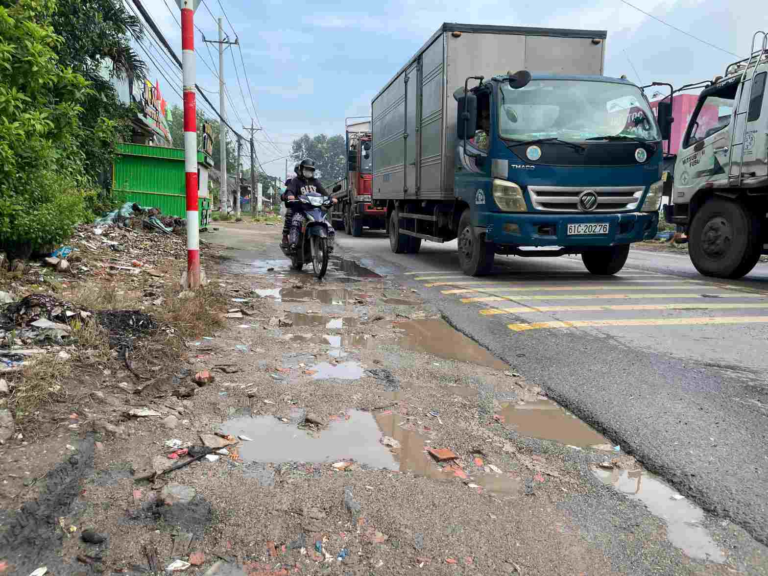 Đường hẹp chưa có vỉa hè, xe tải nhiều, các xe máy phải nép sát vào lề. Ảnh: Đình Trọng