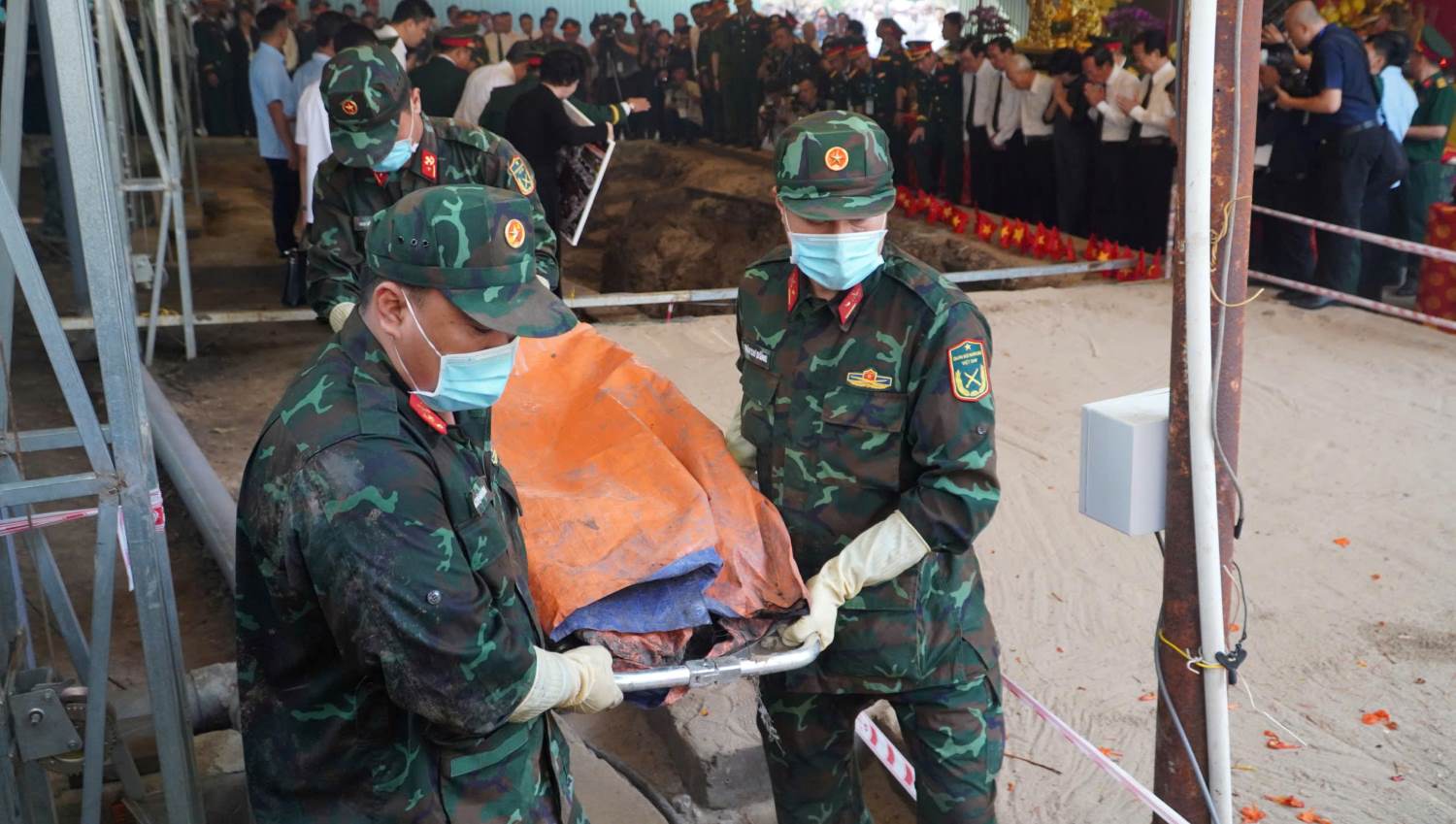 Các chiến sĩ đưa các hài cốt liệt sĩ đã tìm kiếm được từ hố chôn tập thể ra ngoài. Ảnh: Anh Tú