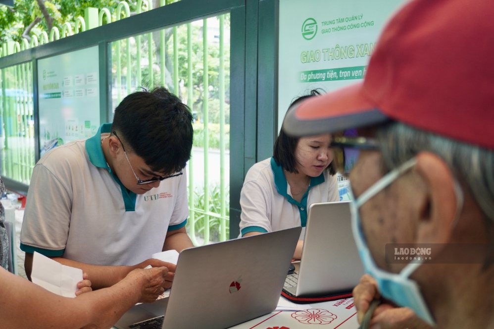 Tình nguyện viên hỗ trợ tra cứu tên trong danh sách nhận thẻ cho người dân.